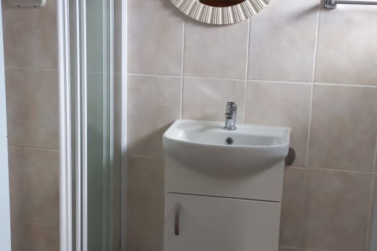 A compact bathroom featuring a shower enclosure, a modern vanity basin, and neutral wall and floor tiling.
