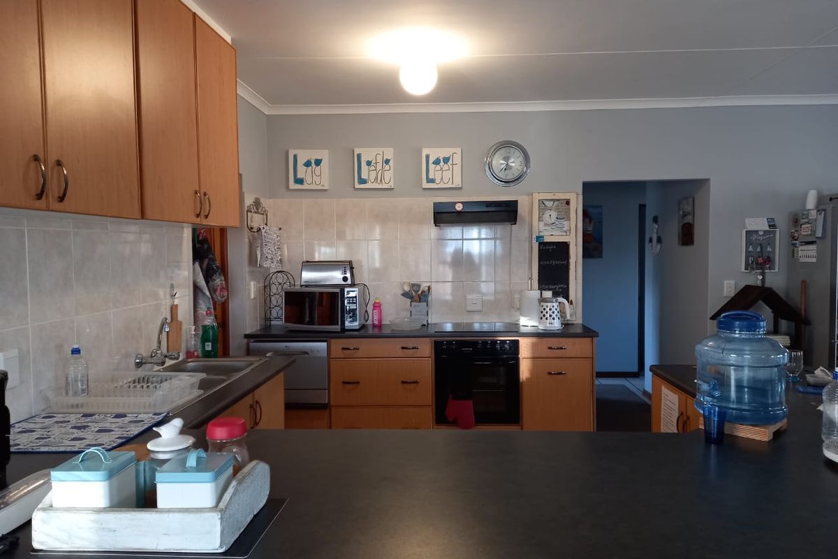 Functional kitchen featuring laminate cabinetry, tiled backsplash, built-in oven, and extractor fan with a breakfast bar counter.