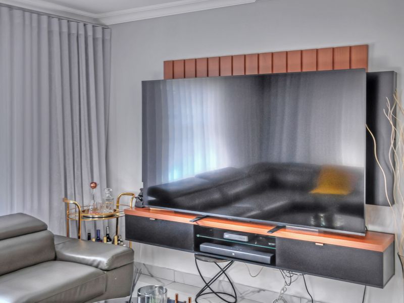 A modern living room featuring a sleek wall-mounted media console, tiled flooring, and elegant floor-to-ceiling curtains.