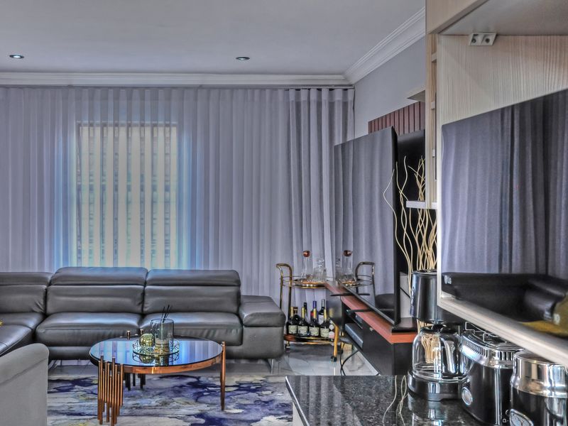 A well-appointed living room featuring recessed lighting, crown molding, and a sleek granite-topped built-in unit, creating a comfortable and modern living space.