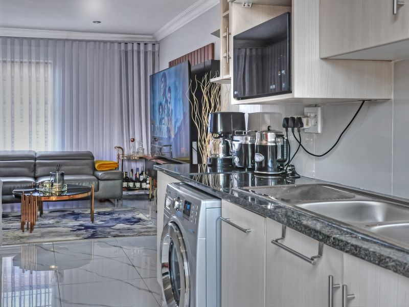 Modern open-plan living area featuring a sleek kitchen with granite countertops, built-in cabinetry, and integrated appliances, flowing seamlessly into the adjacent lounge space.