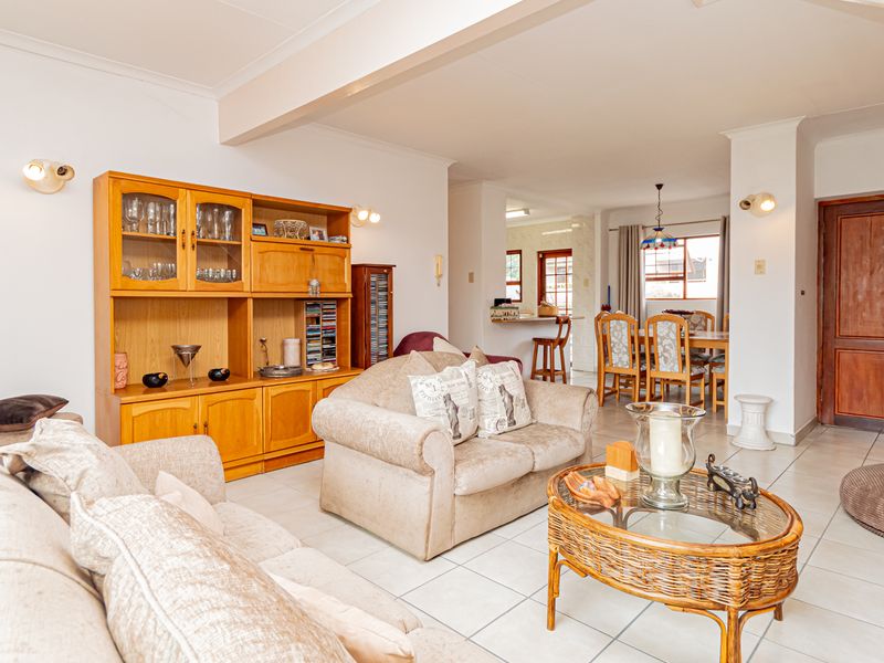 Spacious open-plan living and dining area featuring tiled flooring, neutral walls, and a breakfast bar connecting to the kitchen space.