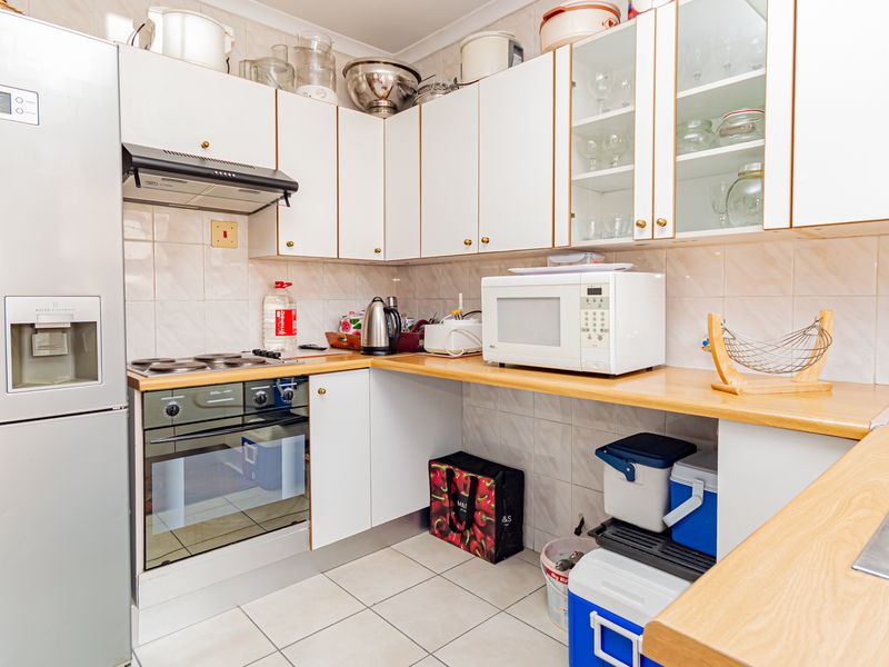A functional kitchen featuring laminate countertops, tiled backsplash, built-in oven with hob, extractor fan, and ample upper and lower cabinetry storage.
