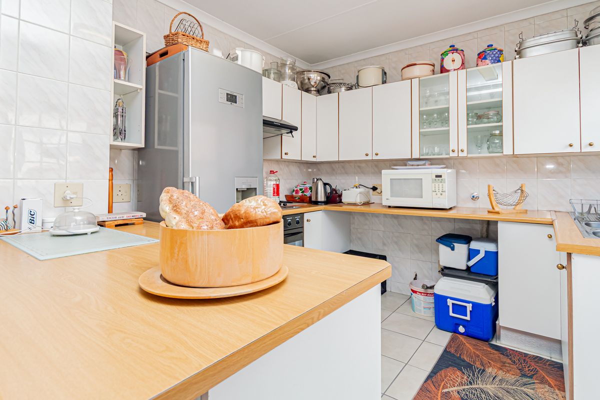 A functional kitchen featuring laminate countertops, ample built-in cabinetry, a tiled backsplash, and a stainless steel sink.