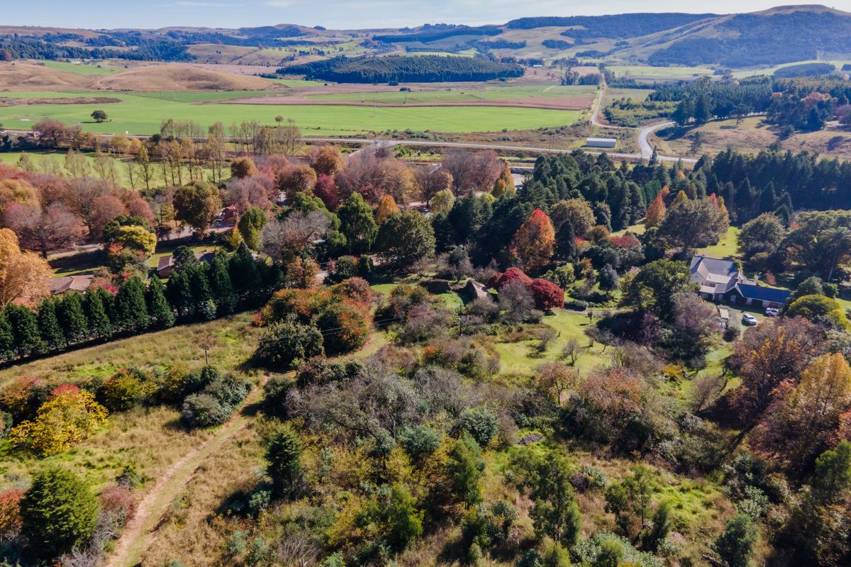 An expansive aerial view of the property grounds, showcasing mature trees, landscaped gardens, and the surrounding rural landscape.