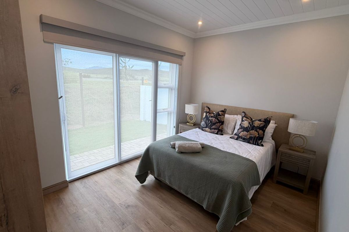 A modern, well-maintained bedroom featuring laminate flooring, a tongue and groove ceiling, and large sliding glass doors providing natural light and outdoor access.