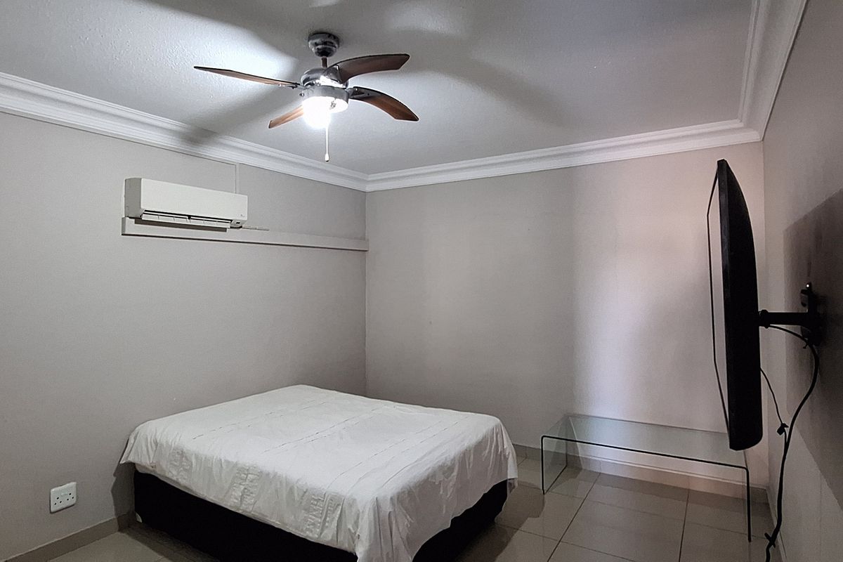 A bedroom featuring tiled flooring, crown molding, a ceiling fan, and a wall-mounted split-system air conditioner.