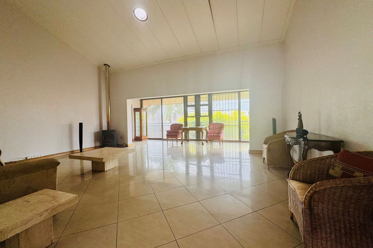 Spacious living room featuring large format floor tiles, a built-in fireplace, and expansive glass sliding doors providing natural light and garden access.