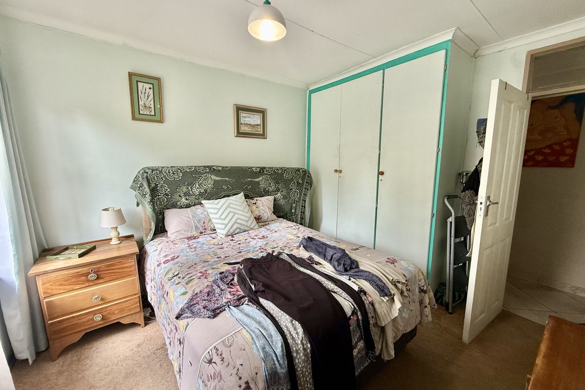 A bedroom featuring built-in wardrobe storage, carpeted flooring, and a standard ceiling light fixture.