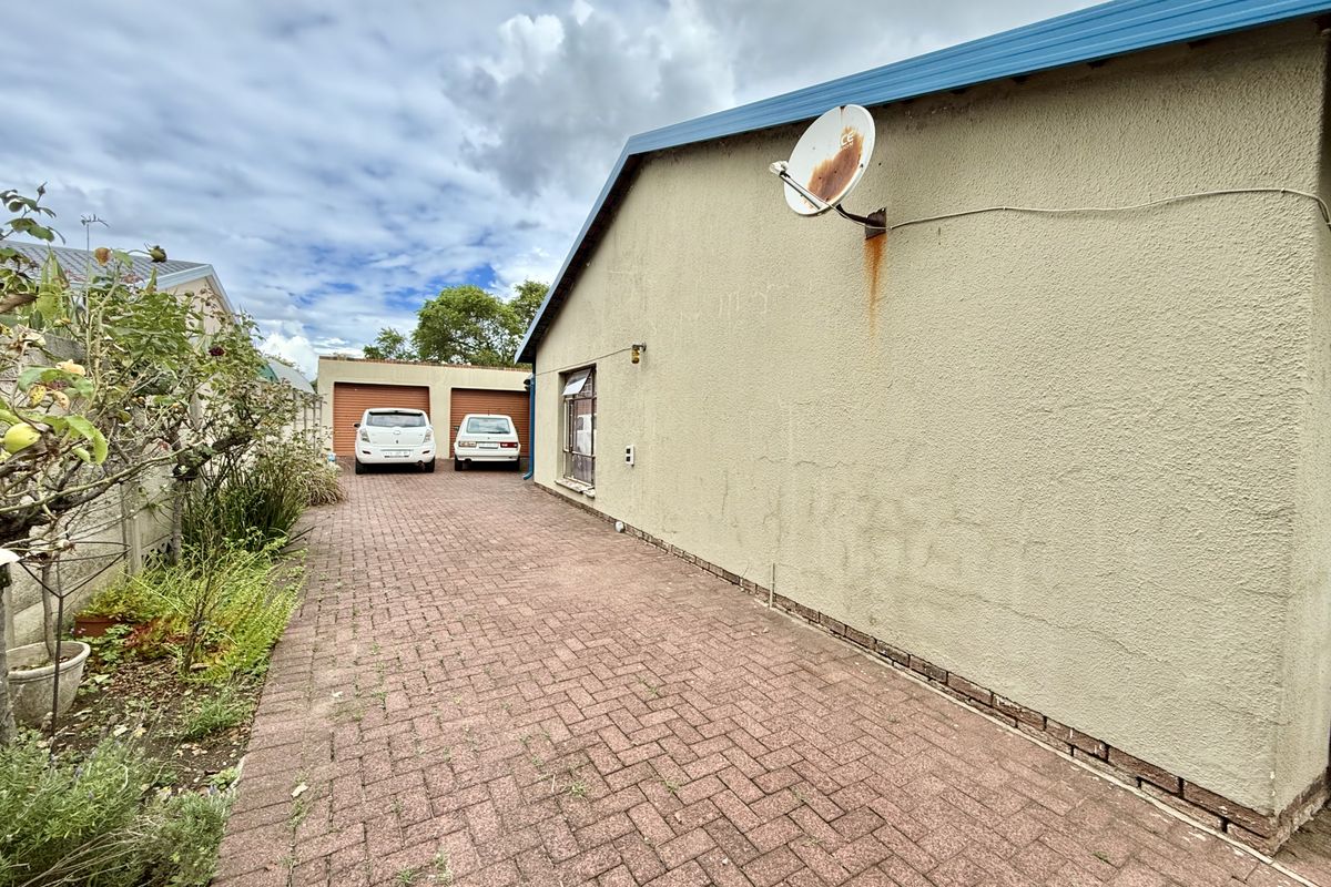 Side view of the property featuring a paved driveway leading to a double garage with a textured exterior wall finish.