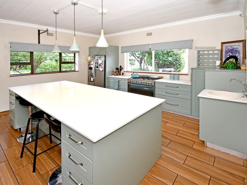 Modern kitchen featuring a large central island with quartz countertops, ample built-in cabinetry, gas stove, and wood-look tiled flooring.