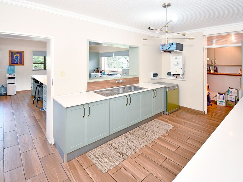 A functional kitchen area featuring light-toned cabinetry, a stainless steel sink, and tiled flooring, with an adjacent scullery and inverter system installed.