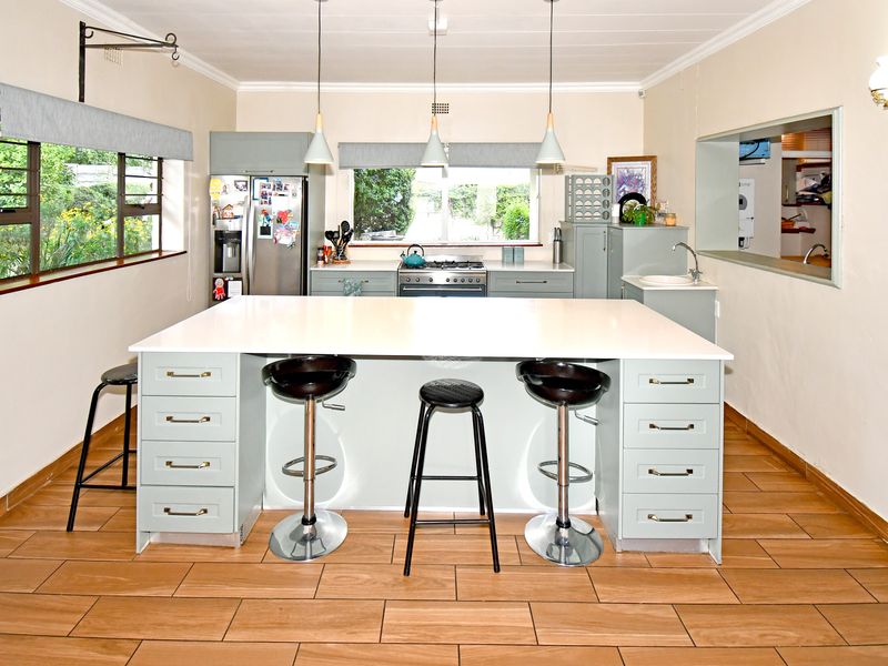 A well-lit kitchen featuring a large central island with quartz countertops, ample cabinetry, gas stove, and modern tiled flooring.