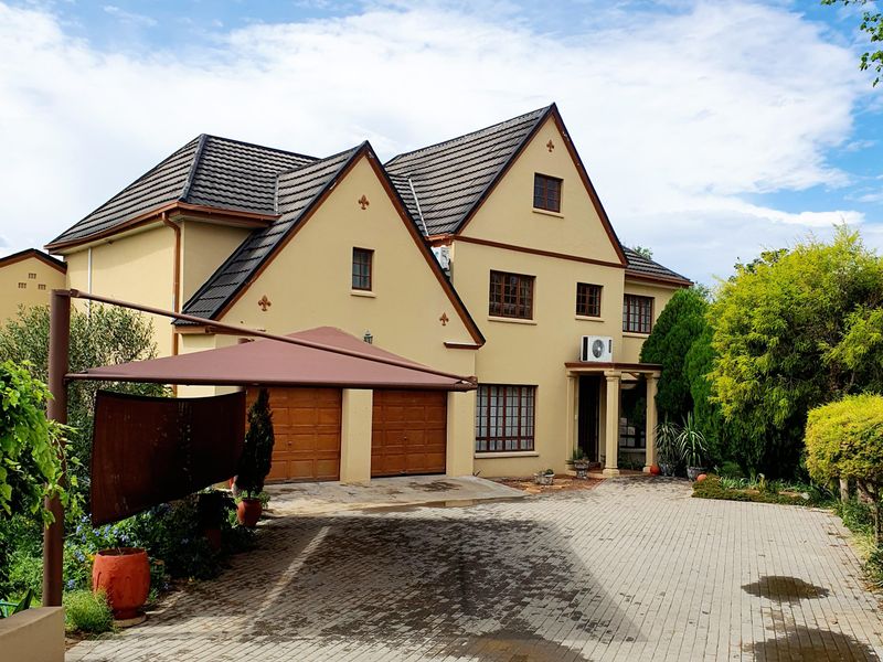 Front elevation of a double-story house featuring a paved driveway, double garage, and a shade sail structure.