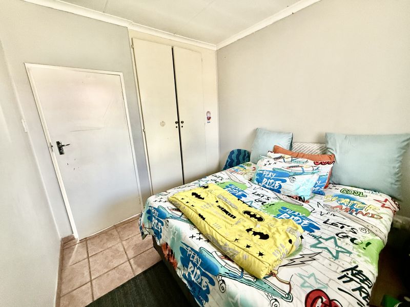 A functional bedroom featuring built-in cupboards and tiled flooring, offering a neutral base for potential interior updates.