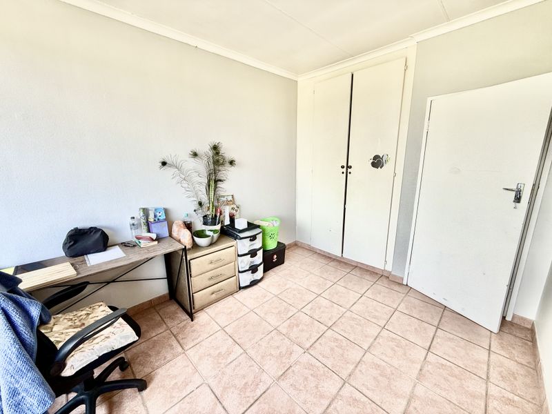 A bedroom featuring tiled flooring and built-in cupboards, providing a functional space with neutral wall finishes.