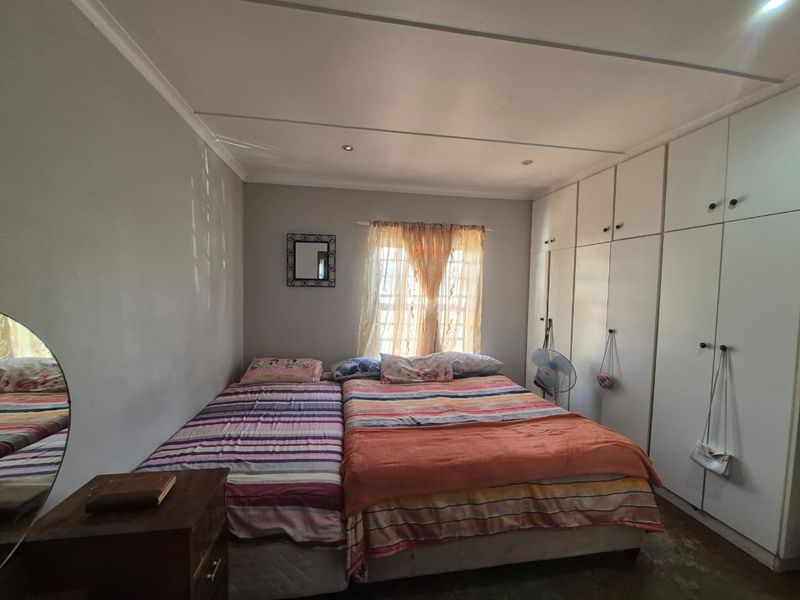 A bedroom featuring extensive floor-to-ceiling built-in cupboards and recessed ceiling lighting, providing ample storage and functional space.