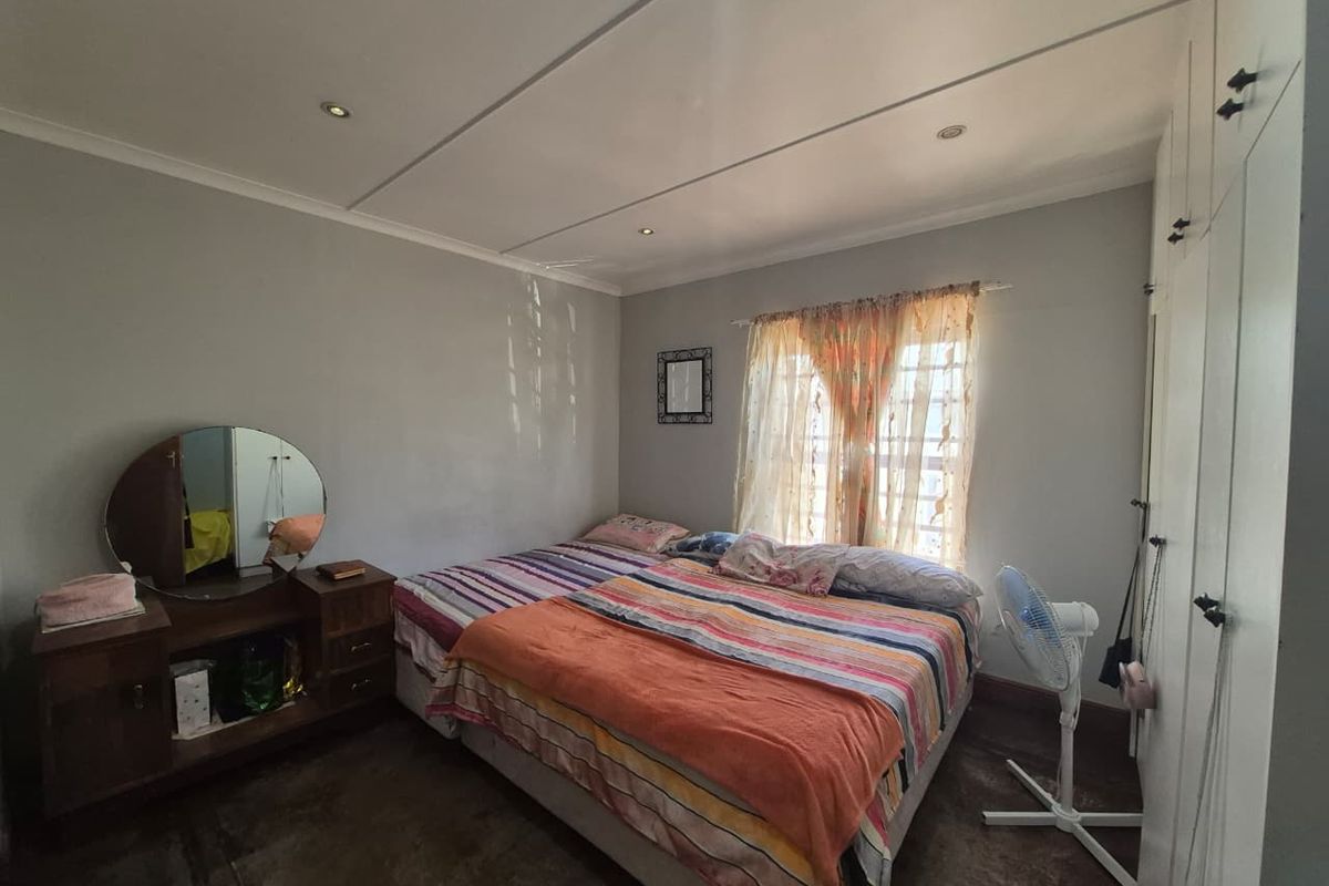 A bedroom featuring built-in cupboards, recessed downlighting, and security bars on the window.