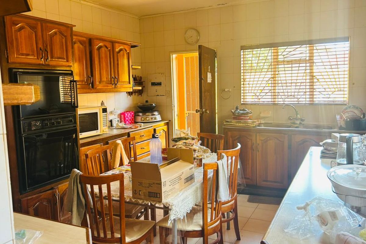 A dated kitchen featuring traditional wooden cabinetry, a built-in double oven, and tiled surfaces, offering a functional layout with potential for modern renovation.