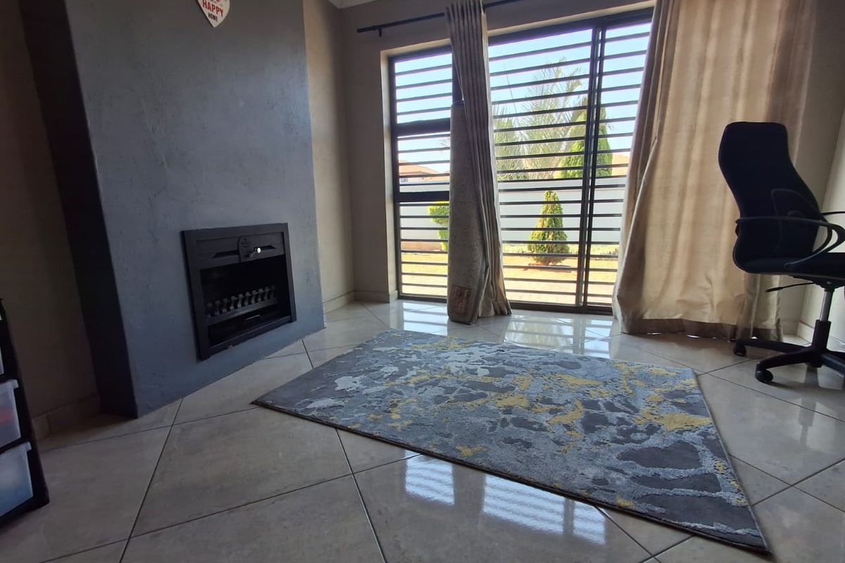 A living room featuring a built-in fireplace, tiled flooring, and a sliding door with security bars leading to the exterior.