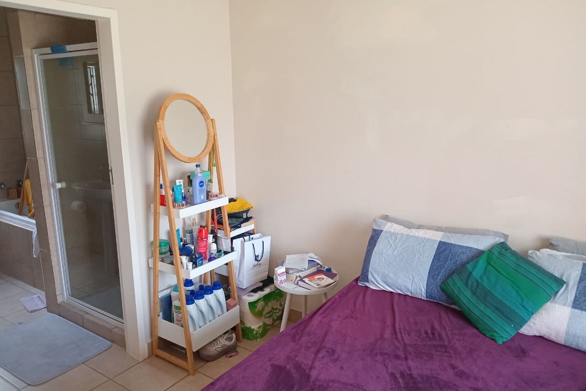 A bedroom featuring tiled flooring and an adjoining en-suite bathroom equipped with a shower enclosure and a built-in bathtub.