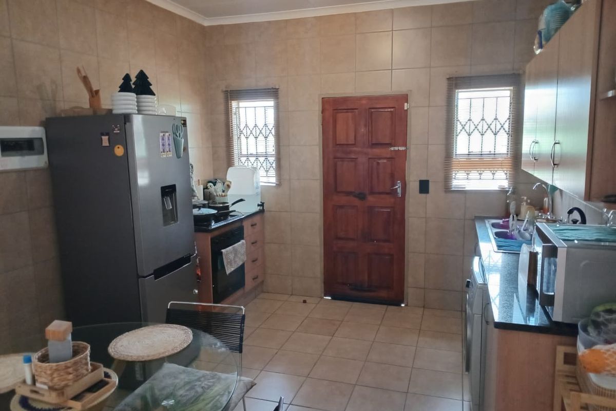 Functional kitchen featuring tiled walls and floors, granite countertops, built-in cabinetry, and direct access to the exterior via a wooden door.