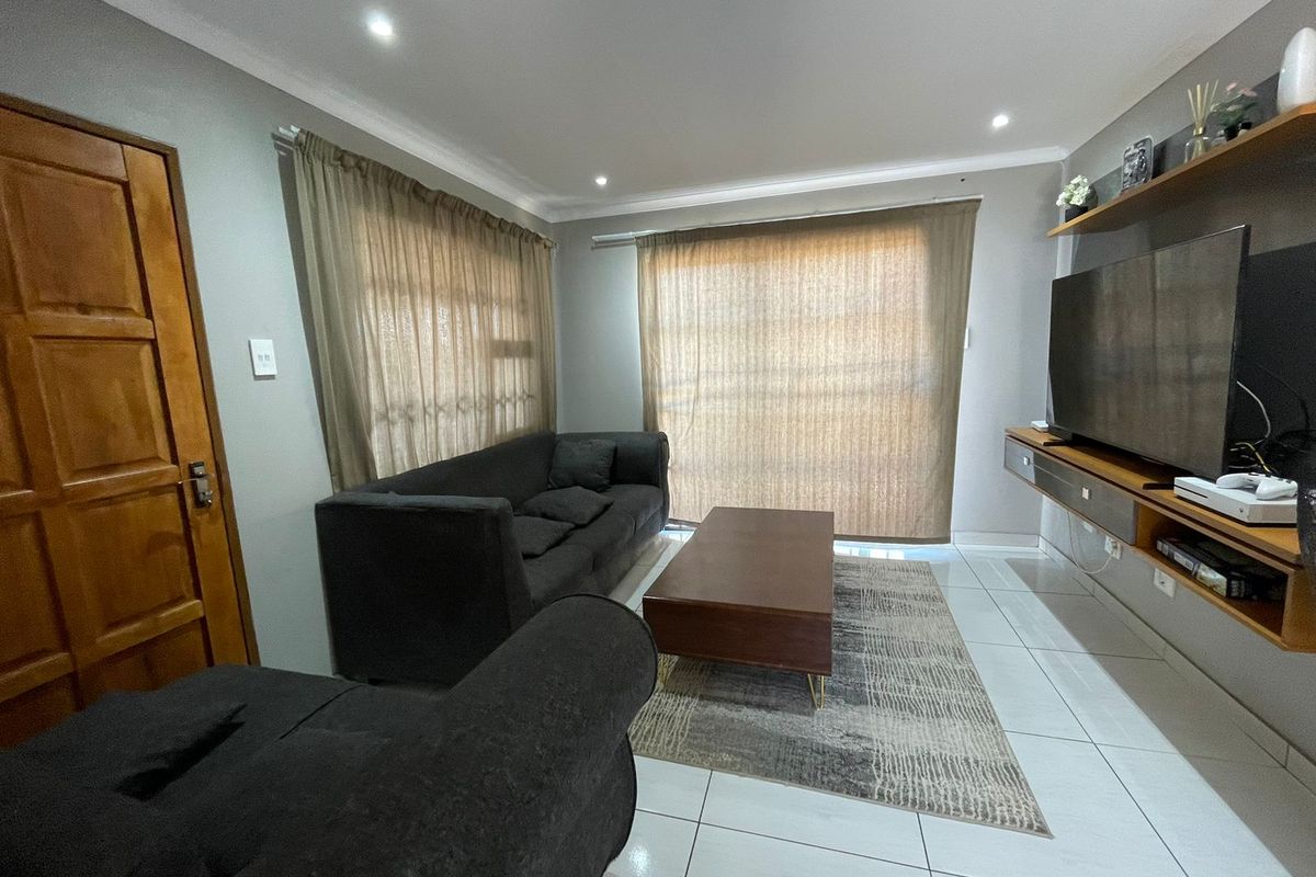 A well-maintained living room featuring tiled flooring, recessed downlighting, and built-in wall shelving, creating a functional and comfortable space.