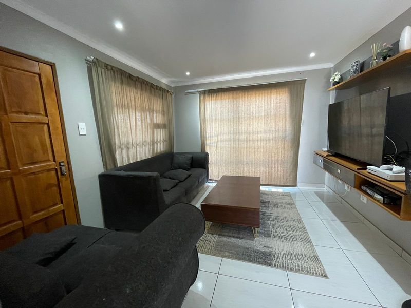 A well-maintained living room featuring tiled flooring, recessed downlighting, and built-in wall shelving, creating a functional and comfortable space.