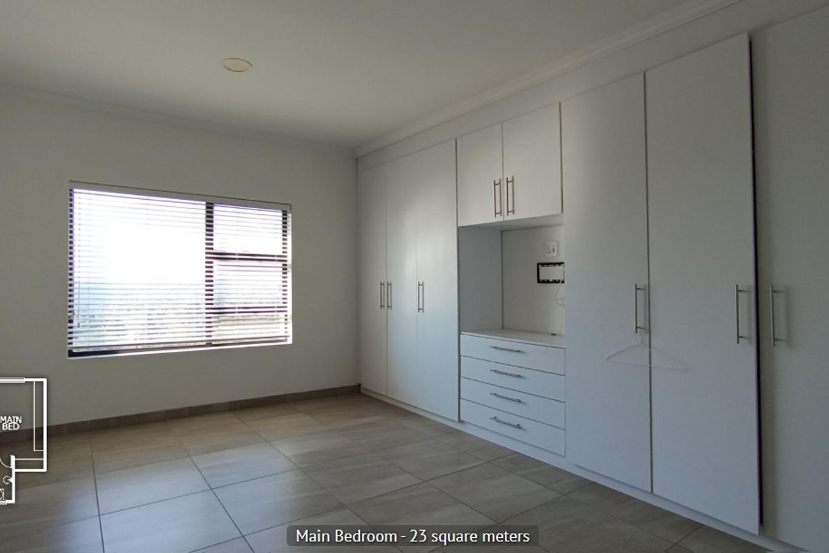 Spacious main bedroom featuring extensive built-in cupboards, neutral tiled flooring, and large windows with fitted blinds.