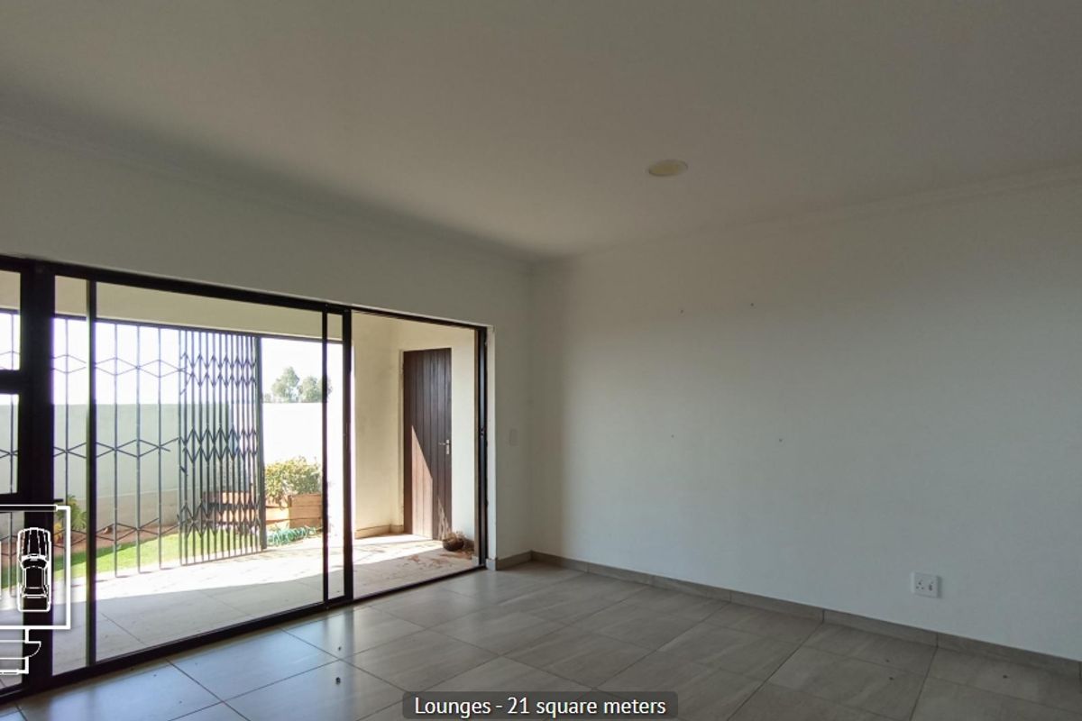 Spacious living area featuring large sliding glass doors that open onto a patio, with neutral tiled flooring and recessed lighting.