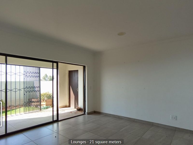 Spacious living area featuring large sliding glass doors that open onto a patio, with neutral tiled flooring and recessed lighting.