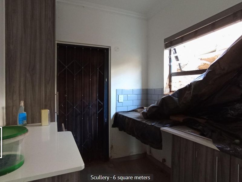 A small scullery area featuring built-in cabinetry and a tiled splashback, currently requiring repairs to the window and general finishing.