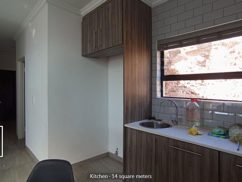 A compact kitchen area featuring modern wood-look cabinetry, a subway tile backsplash, and a stainless steel sink with a window view.