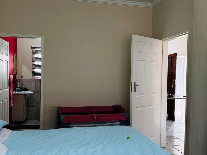 A bedroom featuring built-in cupboards and coving, with direct access to an en-suite bathroom and a hallway.