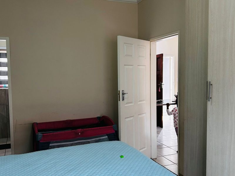 A bedroom featuring built-in wardrobes and neutral wall finishes, providing a functional space with direct access to an adjoining room.