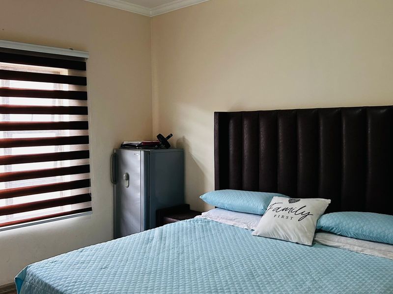 A bedroom featuring neutral walls, crown molding, and modern zebra blinds, providing a functional space for rest.