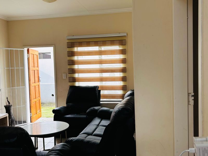 A living room area featuring zebra blinds, a security gate at the entrance, and neutral wall finishes.