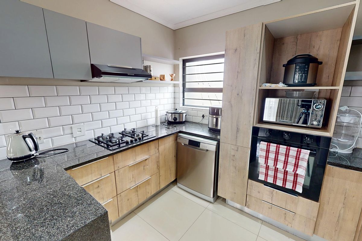 Modern kitchen featuring granite countertops, subway tile backsplash, built-in oven, gas hob, and integrated cabinetry with a clean, contemporary finish.