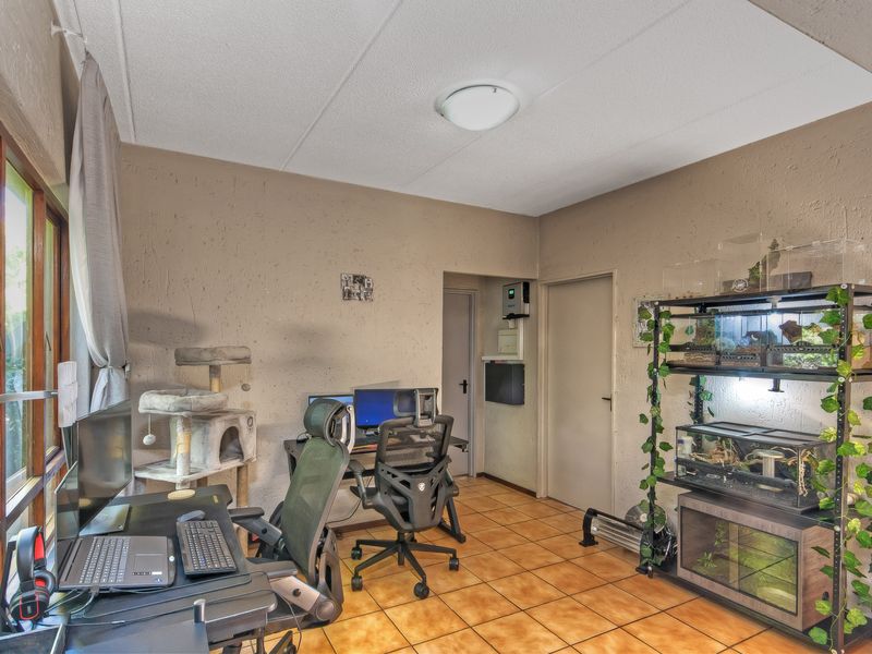 A functional office space featuring tiled flooring, textured walls, and a flush mount ceiling light, suitable for a home workspace.