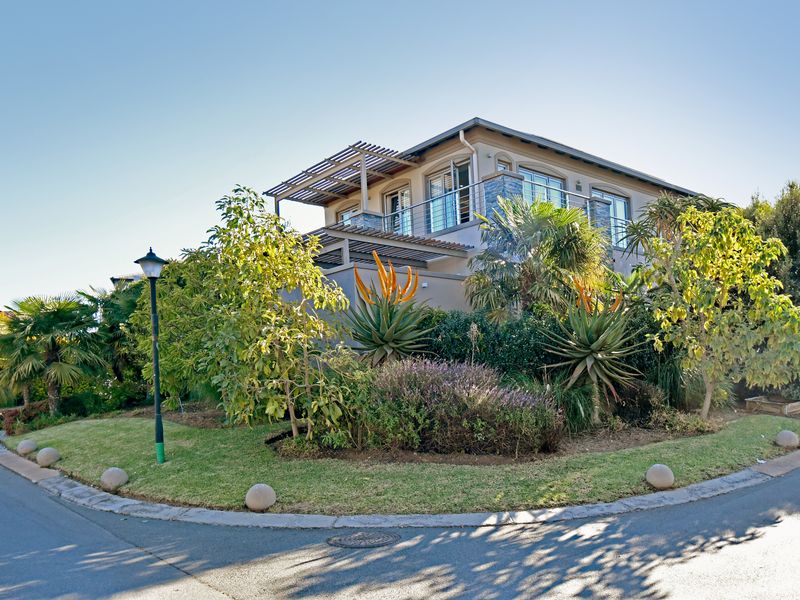 A well-maintained double-story residential property featuring a modern balcony with pergola, stone-clad accents, and established landscaped garden.