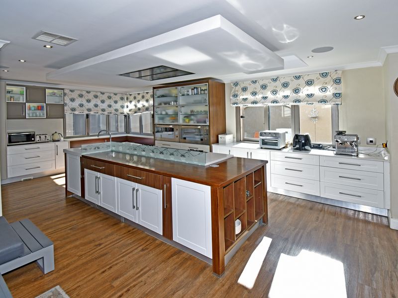 Spacious modern kitchen featuring a large central island with wood and white cabinetry, integrated ceiling lighting, and ample storage space.