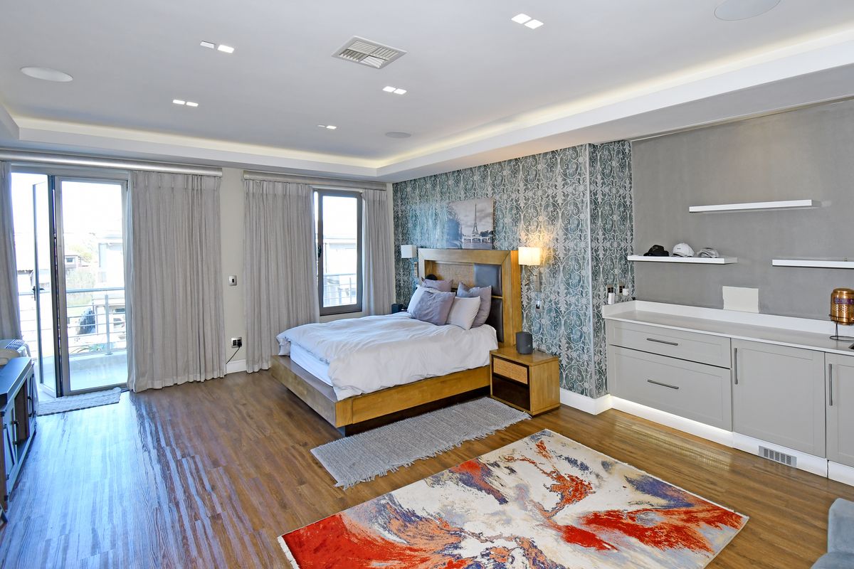 Spacious bedroom featuring recessed ceiling lighting, built-in cabinetry with shelving, wood-look flooring, and direct access to a private balcony.