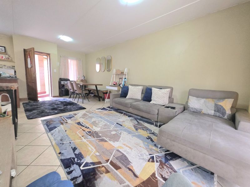 An open-plan living and dining area featuring tiled flooring and direct access to an exterior entrance.