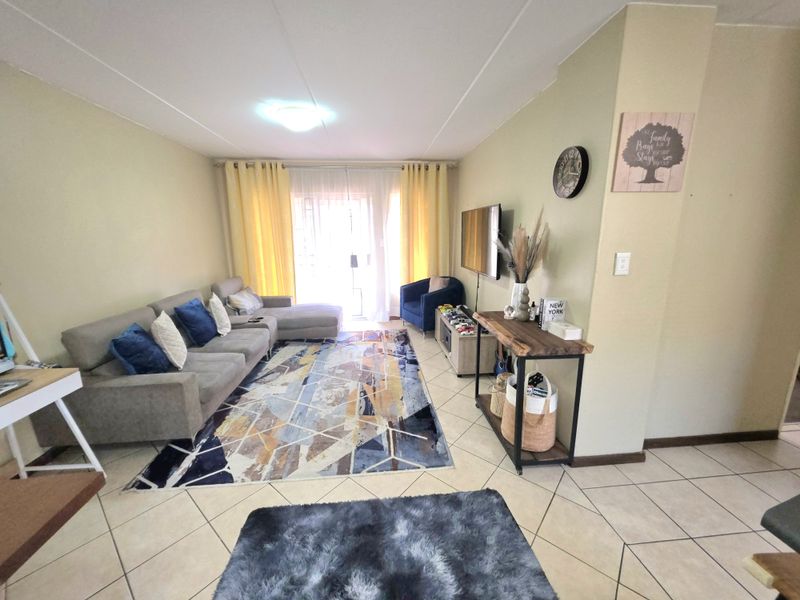 A spacious living room featuring tiled flooring, neutral wall tones, and a sliding glass door providing access to an outdoor area.
