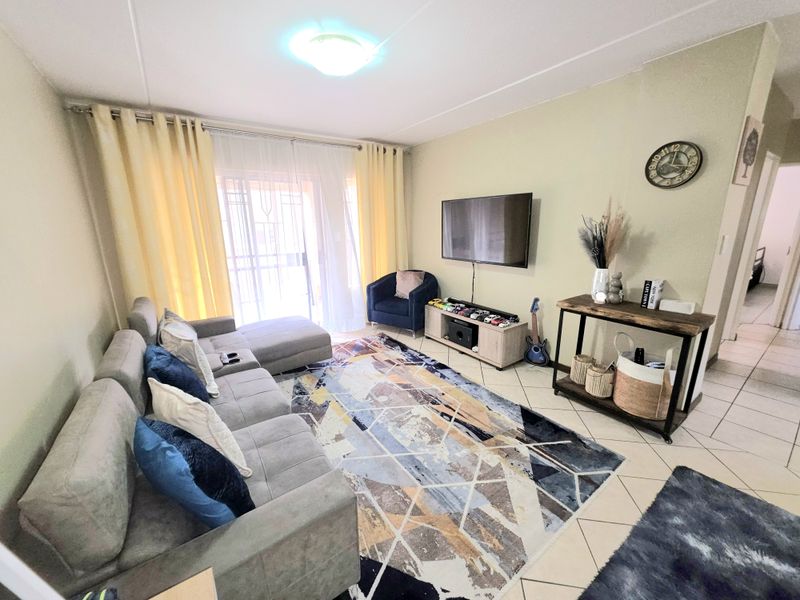 A comfortable living room featuring tiled flooring, a sliding door leading to a balcony, and neutral wall finishes.
