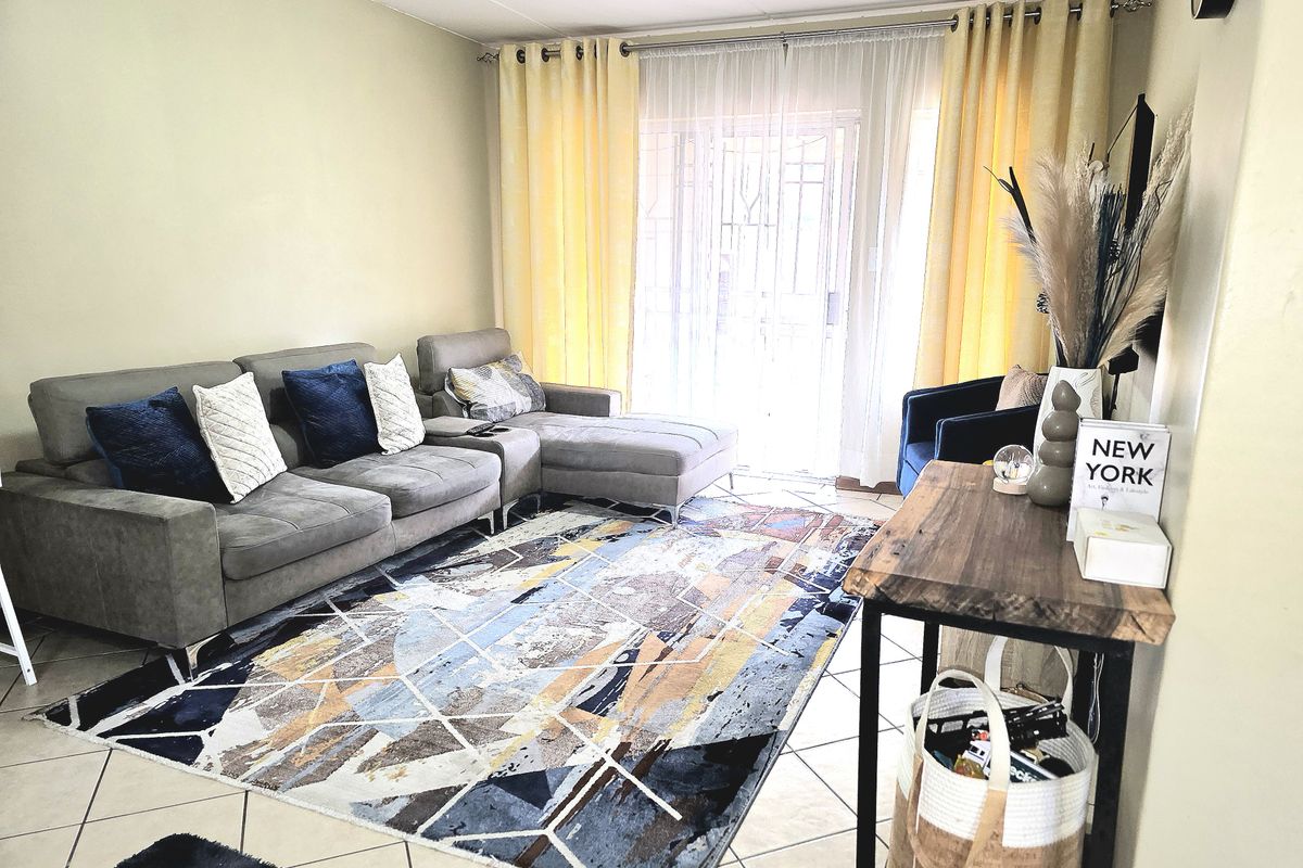 A bright living room featuring tiled flooring and a sliding glass door leading to an outdoor area, providing natural light to the space.