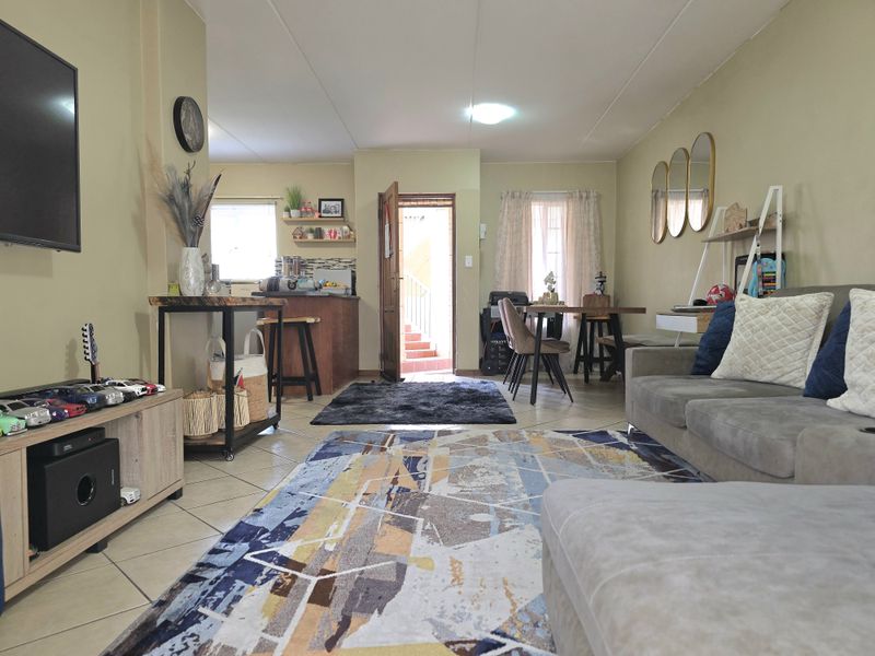 An open-plan living and kitchen area featuring tiled flooring, a breakfast counter, and direct access to an exterior entrance.