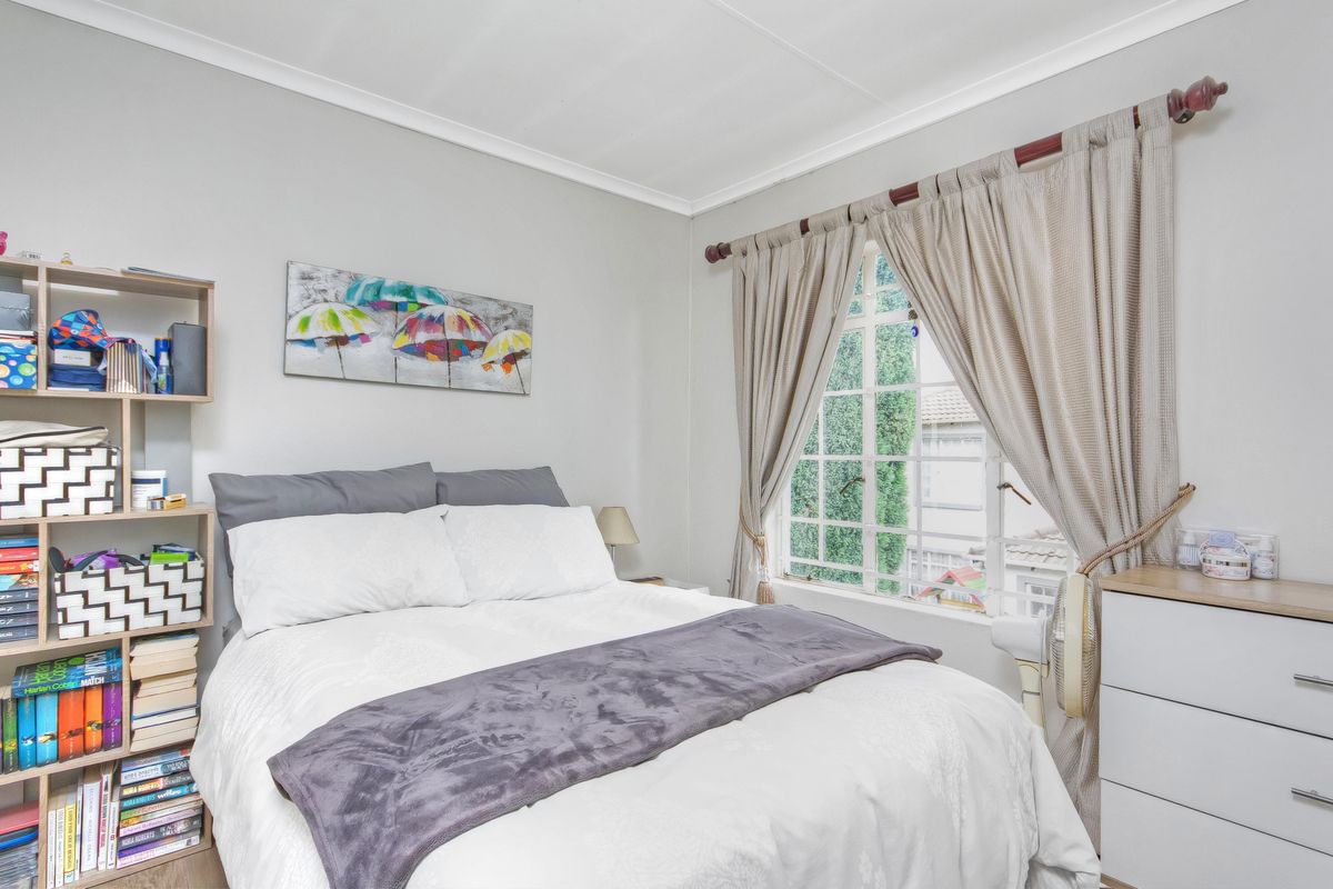 A well-maintained bedroom featuring a lattice window with curtain rod and classic cove cornice detailing.