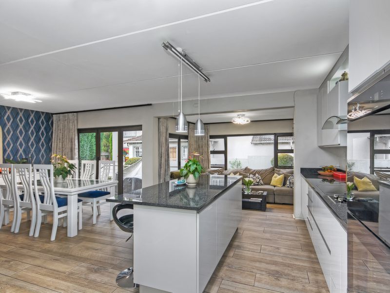 Open-plan living area featuring a modern kitchen with a central island, granite countertops, integrated oven, and seamless flow to the dining and lounge spaces.