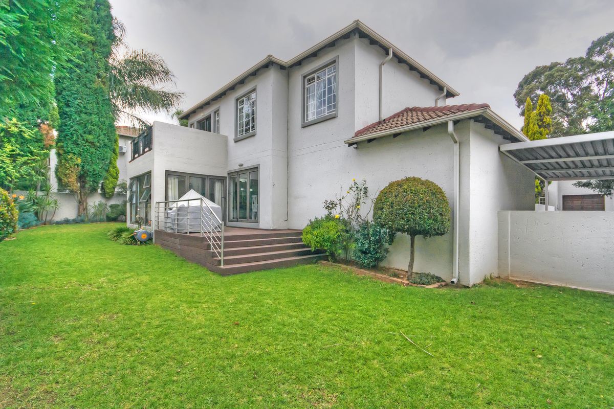 Rear view of the townhouse featuring a raised timber deck, sliding glass doors, and a well-maintained private garden area.